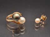une paire de bagues et de boucles d'oreilles en perles et en or posées sur un fond noir