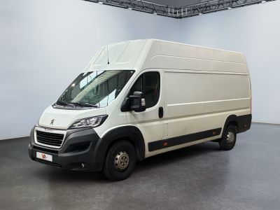 La camionnette blanche est garée dans une grande pièce au sol noir