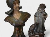 two statues of a woman and a dog on a white surface