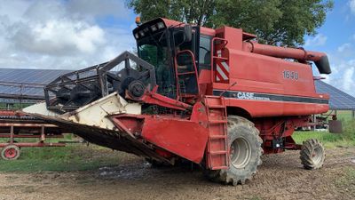 une moissonneuse-batteuse rouge qui est à l'arrêt dans la terre