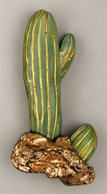 a green and gold cactus sitting on top of a rock