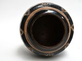 a black and gold vase on a white surface