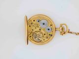 a gold pocket watch on a chain on a white surface