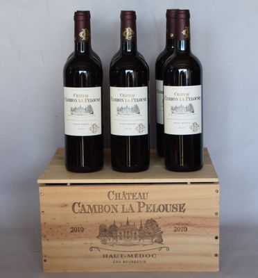 trois bouteilles de vin rouge dans une caisse en bois posée sur une table