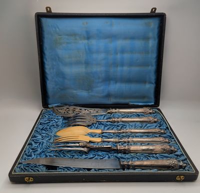 un service d'argenterie ancienne présenté dans un coffret noir doublé de velours bleu
