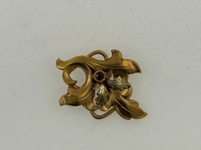 a gold brooch with a flower and leaves on it