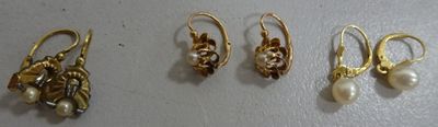 three pairs of gold earrings with pearls and leaves on them