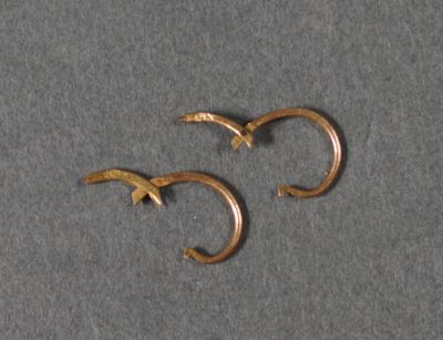 deux boucles d'oreilles en or posées sur une surface grise
