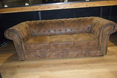 un canapé en cuir marron posé sur un parquet en bois massif