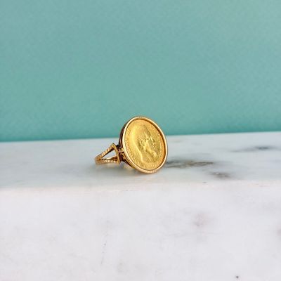 une bague en forme de pièce d'or posée sur un comptoir en marbre