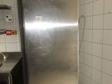 un réfrigérateur en acier inoxydable dans une cuisine aux murs carrelés