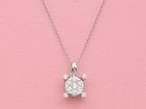 un pendentif en forme de tortue en diamant blanc, suspendu à une chaîne, sur fond rose
