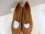 pair of women ' s tan shoes with holes on them on a white surface