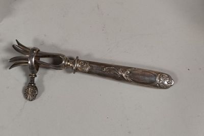 une cuillère en argent sur laquelle repose un couteau, posée sur une surface blanche