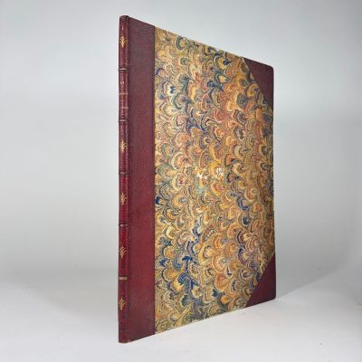 un vieux livre à la couverture rouge, ornée d'un motif doré et bleu
