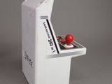 a small toy arcade machine with a red ball on top of it