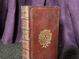 un vieux livre posé sur une table, à côté d'un rideau violet