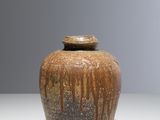 a brown vase sitting on a table with a gray background