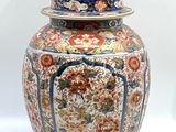 un grand vase muni d'un couvercle, posé sur une surface blanche