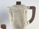 a silver teapot with a wooden handle next to a silver teapot