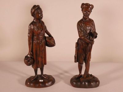 pair of wooden statues of a man and a woman holding baskets
