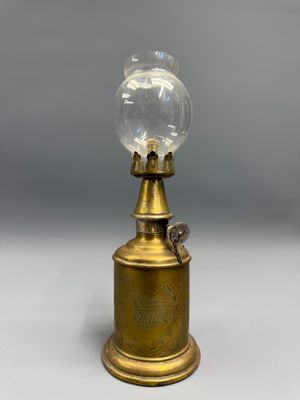 une lampe à huile ancienne en laiton, surmontée d'un globe en verre