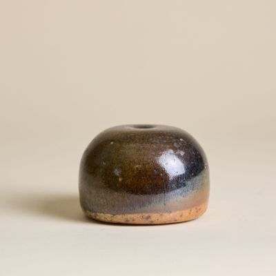 un petit objet marron et noir posé sur une surface blanche