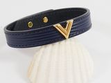 a close up of a black leather bracelet with a gold v on it