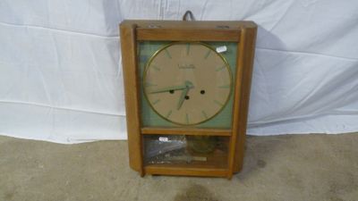 a clock that is sitting on the floor in front of a white wall
