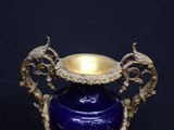 a blue vase with a gold handle on a black background