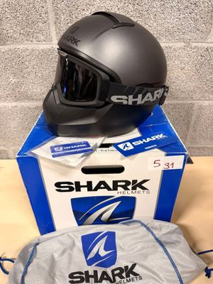 the shark helmet is sitting on top of the box next to the bag