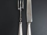 two knives and a fork on a black table