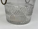a glass ice bucket with a handle on a table