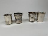 trois verres à shot en argent et un verre à shot en argent posés sur une surface blanche