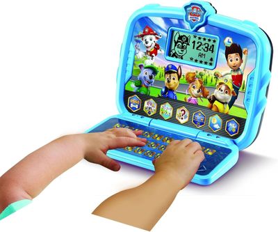 a small child playing with a laptop computer on the table