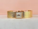 gros plan d'une montre-bracelet en or sur une surface blanche