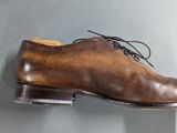brown leather shoes hanging on a wall with a grey background