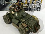 a toy army vehicle with soldiers on it next to a book