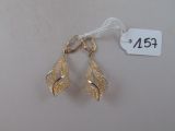 une paire de boucles d'oreilles dorées sur fond blanc, avec une étiquette de prix