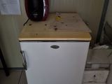a small white refrigerator with a coffee maker on top of it