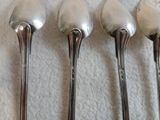 trois cuillères en argent posées sur une nappe blanche