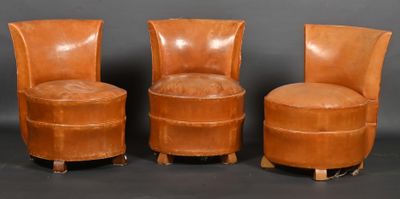 trois fauteuils en cuir marron placés les uns à côté des autres sur une surface noire