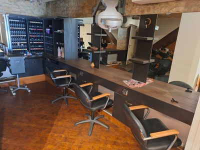 une photo d'un salon de coiffure avec des fauteuils et un comptoir