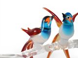 three glass birds sitting on a branch of a tree