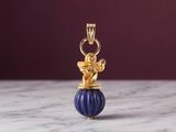 a close up of a gold and blue bead charm on a marble surface