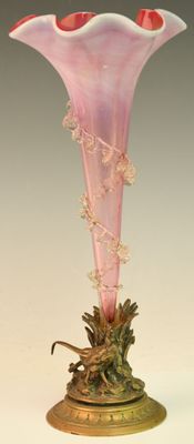 un vase en verre rose avec un socle doré posé sur une table