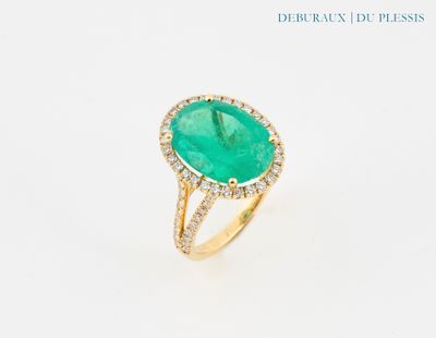 gros plan d'une bague avec une pierre verte entourée de diamants