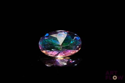 a close up of a rainbow colored diamond on a black surface
