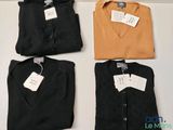three shirts with tags on them sitting on top of a table