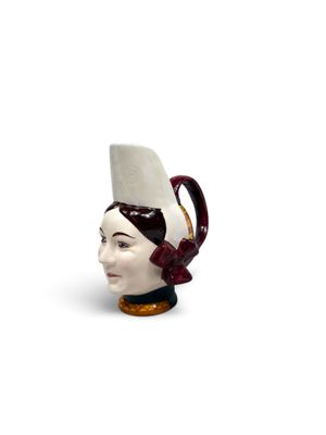 un mug en céramique en forme de tête de femme coiffée d'un chapeau